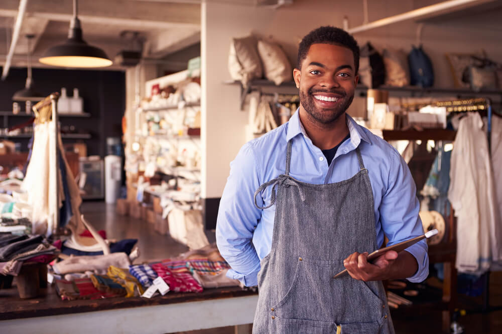 Vendedor sorrindo para o cliente, com almofadas ao fundo.