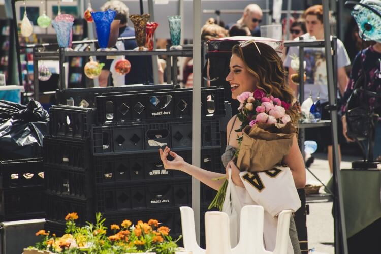 Cliente sorrindo dentro de uma loja, segurando um buquê de flores.