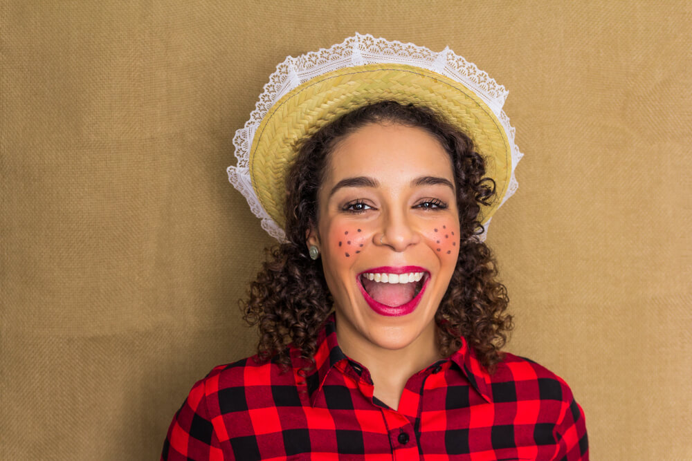 Funcionária com trajes caipiras combinando com decoração de festa junina para loja.