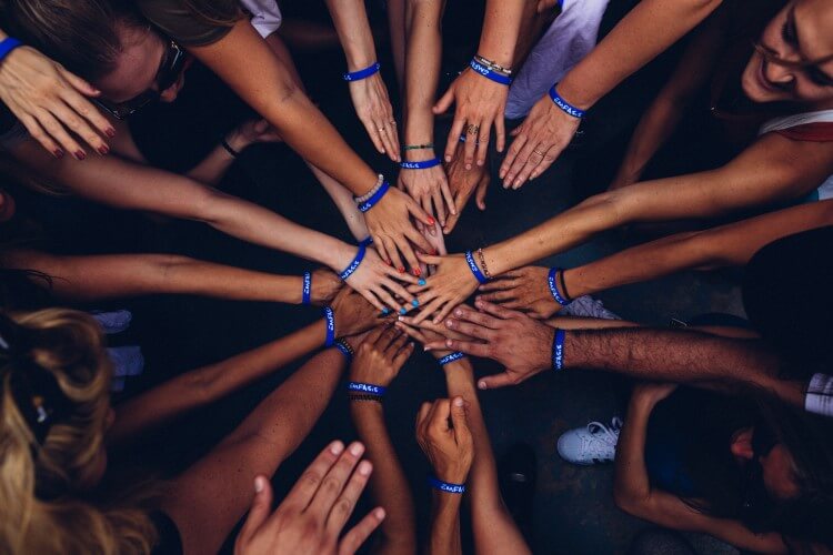 Membros de uma equipe unindo as mãos em círculo.