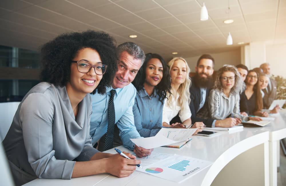 Funcionários sentados na mesa para reunião de trabalho.