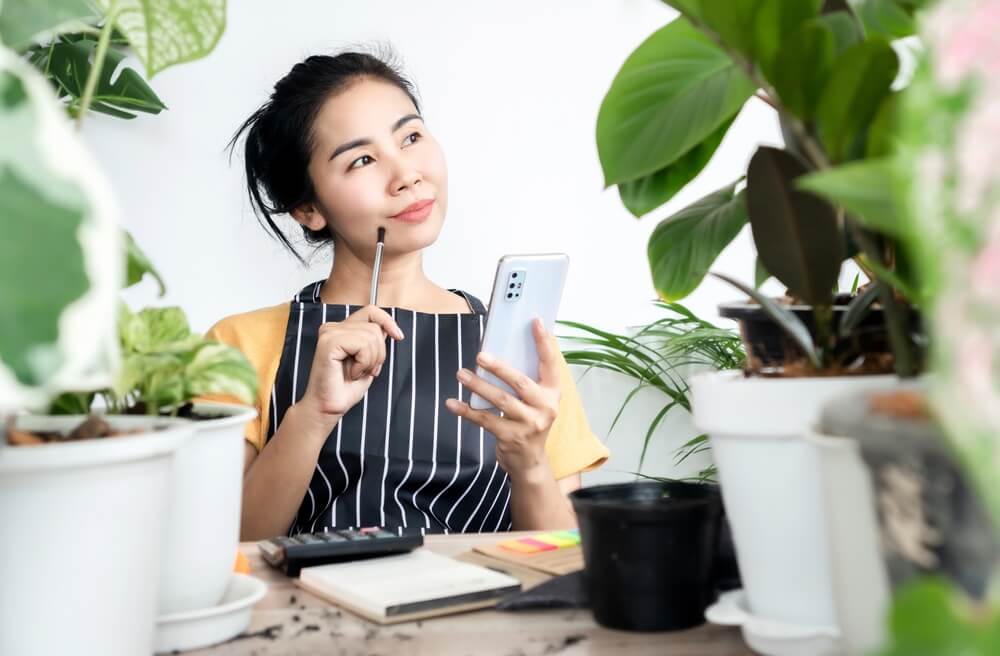 Imagem de uma mulher. Ela está pensando se vai finalizar uma compra pelo celular ou não.